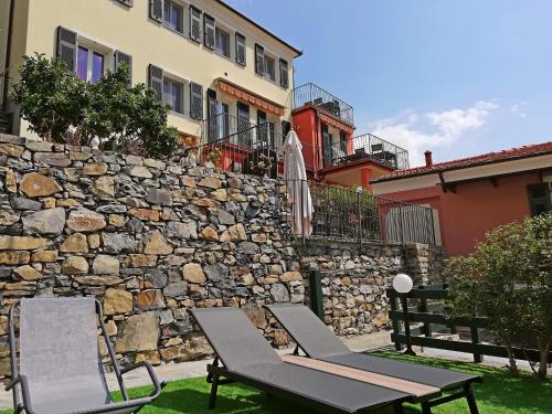 two chairs and an umbrella next to a stone wall at Case Vacanze Borgo Faraldi in Villa Faraldi