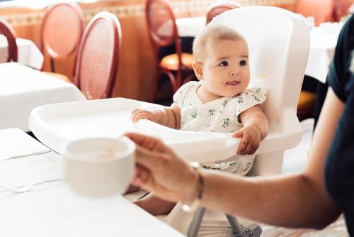 a baby sitting in a high chair at a table at Hotel Brioni Mare in Lido di Jesolo