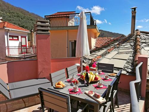 a table with food and a umbrella on a balcony at Case Vacanze Borgo Faraldi in Villa Faraldi