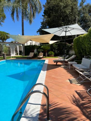 a swimming pool with an umbrella and chairs and a table and an umbrella at Villa Losanna in Mondello