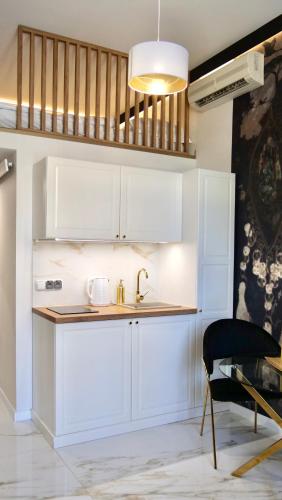 a kitchen with white cabinets and a sink and a chair at Art Apartments Warszawska 21 Katowice in Katowice