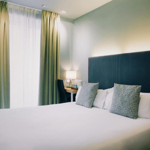 a bedroom with a large white bed with a window at Petit Palace Tres Cruces in Madrid