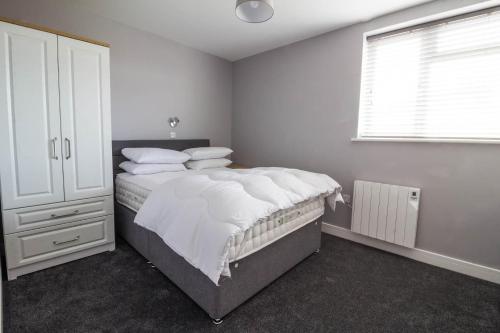 a bedroom with a bed with white sheets and a window at Brilliant 4 Berth Seaside Apartment In Great Yarmouth, Norfolk Ref 99005s in Great Yarmouth