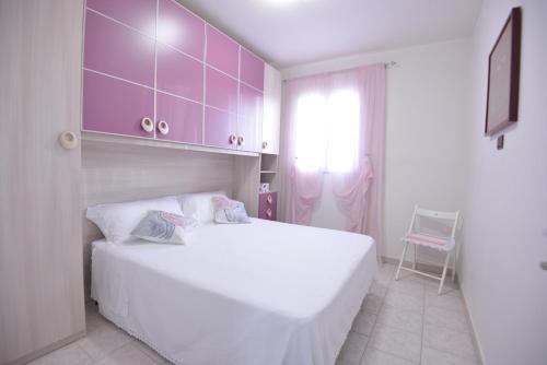 a bedroom with a large white bed and purple cabinets at Villa del Sole in Ostuni