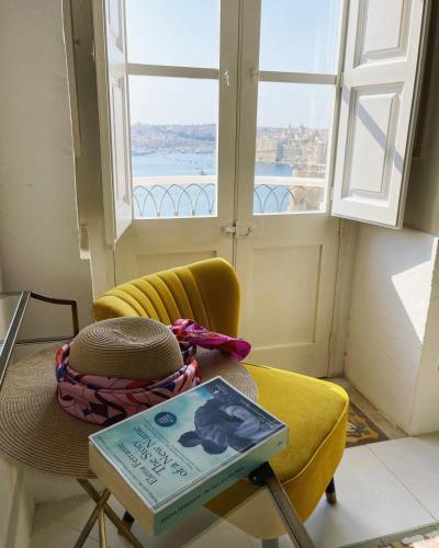 una mesa con un libro y una silla con una ventana en Spacious maisonette with spectacular views IBRI1-1, en La Valeta