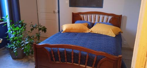 Cama de madera con sábanas azules y almohadas amarillas en Mont Pley, en Esson