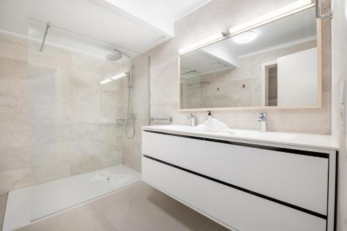 a white bathroom with a sink and a shower at Villa Enderrossall in Porto Cristo