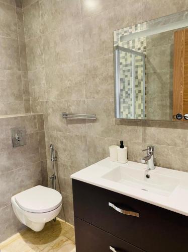 a bathroom with a toilet and a sink and a mirror at Hivernage, Superbe appartement dans une résidence in Agadir