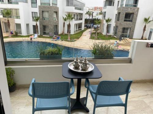 uma mesa e cadeiras numa varanda com vista para a piscina em Hivernage, Superbe appartement dans une résidence em Agadir