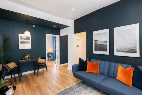 a living room with a blue couch and orange pillows at Crescent Apartments in Newport