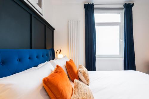 a bed with orange pillows on it with a window at Crescent Apartments in Newport