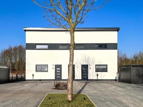 a white building with a tree in front of it at Luxus-Ferienhaus CASA SOL in Göhren-Lebbin