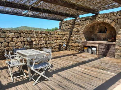 una terrazza in legno con tavolo, sedie e parete in pietra di Kuddia Attalora a Pantelleria