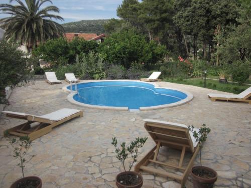 einen Pool mit 2 Liegestühlen und eine Terrasse in der Unterkunft Family friendly apartments with a swimming pool Mundanije, Rab - 5076 in Rab