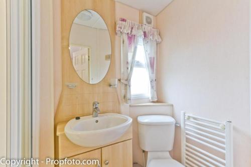 a bathroom with a sink and a toilet and a mirror at By The Seaside Dog Friendly Caravan At Haven Hopton In Norfolk Ref 80015w in Great Yarmouth