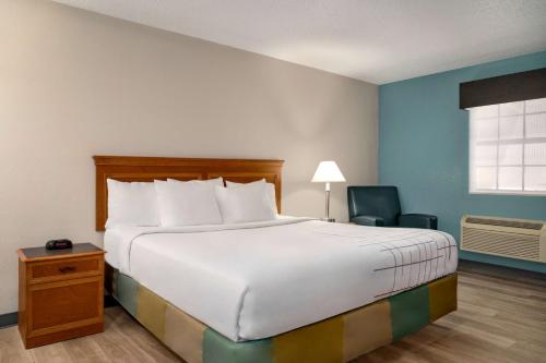 a bedroom with a large bed and a chair at La Quinta Inn by Wyndham Columbus Airport Area in Columbus