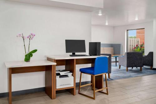 an office with a desk with a computer and a blue chair at La Quinta Inn by Wyndham Columbus Airport Area in Columbus