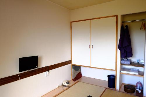 um quarto com um armário branco e uma televisão em Guesthouse Sakuya em Fujikawaguchiko