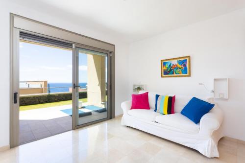 Chalet con vistas al mar en Santa Cruz de Tenerife في سانتا كروث دي تينيريفه: غرفة معيشة مع أريكة بيضاء وباب زجاجي منزلق