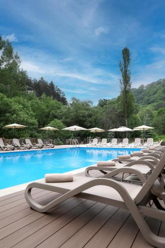 a row of lounge chairs and a swimming pool at Best Western Plus Paradise Hotel Dilijan in Dilijan