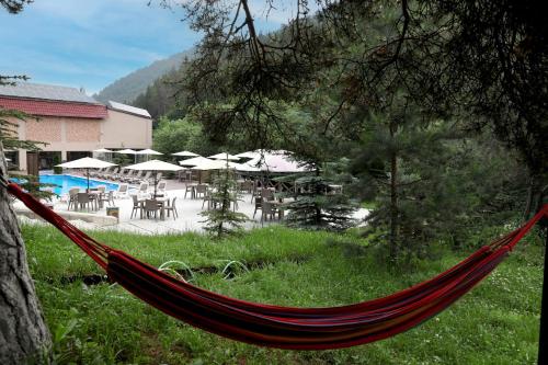 a hammock in front of a patio with tables and umbrellas at Best Western Plus Paradise Hotel Dilijan in Dilijan