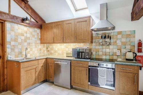 a kitchen with wooden cabinets and a sink and a stove at Ingleborough View in Carnforth