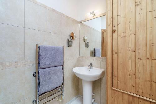 ein Badezimmer mit einem weißen Waschbecken und einer Holztür in der Unterkunft Ingleborough View in Carnforth