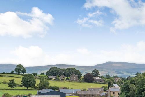 a village in the hills with mountains in the background at Ingleborough View in Carnforth