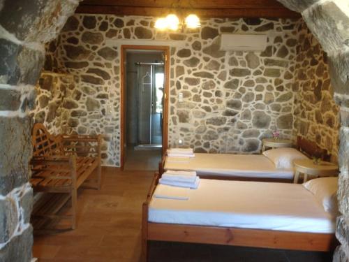 a room with three beds in a stone wall at Loutra Olive Gardens Stone House #1 in Mandrákion