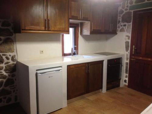 a kitchen with wooden cabinets and a sink and a dishwasher at Loutra Olive Gardens Stone House #1 in Mandrakion