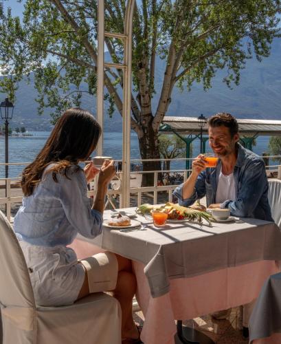 Un hombre y una mujer sentados en una mesa comiendo comida en Hotel Europa - Skypool & Panorama, en Riva del Garda