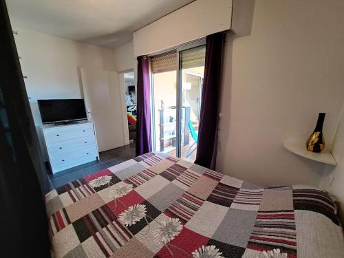 een slaapkamer met een bed met een quilt bij appartement vue mer avec parking in Ajaccio