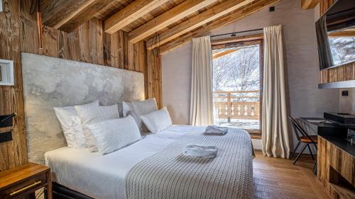 une chambre avec un lit avec des draps blancs et une fenêtre dans l'établissement Chalet Orso - Val d'Isère - 13 pers - 520m2, à Val dʼIsère