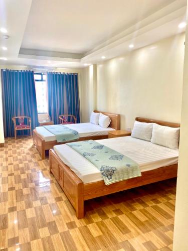 two beds in a room with blue curtains at Chiến Thắng victory hotel in Ha Long