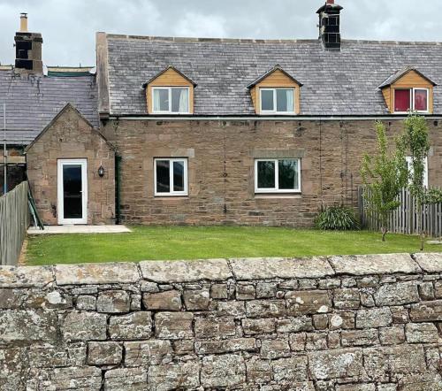 a stone wall in front of a house at Tweed Cottage 4 Fenton Hill in Wooler