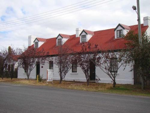 a white house with a red roof on a street at Sorell Barracks in Sorell