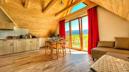 a kitchen and living room with a table and a couch at Apartamenty Widok Tatr in Zakopane