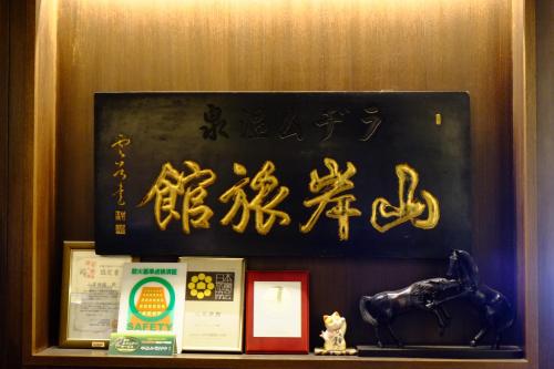 a sign with asian writing on a wall next to a shelf at Yamagisi Ryokan in Fujikawaguchiko