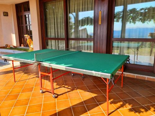 a green ping pong table in a room with windows at B&B Margot in Albavilla