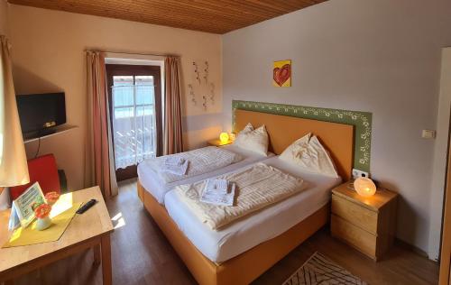 Schlafzimmer mit einem Bett, einem Schreibtisch und einem Fenster in der Unterkunft Pension Göschlberger in Mondsee
