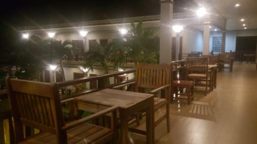 a restaurant with wooden tables and chairs at night at Mama Leurth Sunset Guesthouse in Don Det
