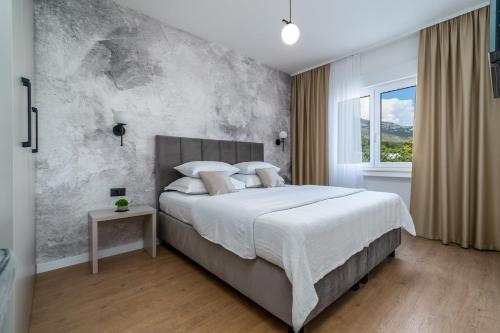 ein Schlafzimmer mit einem großen Bett und einer Betonwand in der Unterkunft Villa Marisa with 51sqm pool, 5 bedrooms, gym in Kaštela