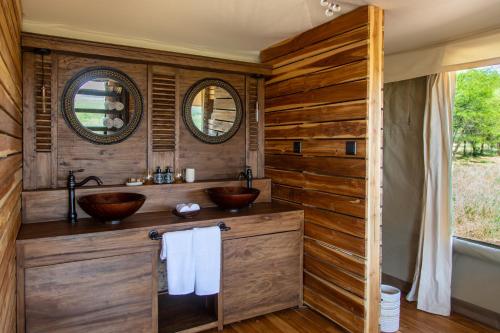 a bathroom with two sinks and two mirrors at Cherero Camp in Serengeti
