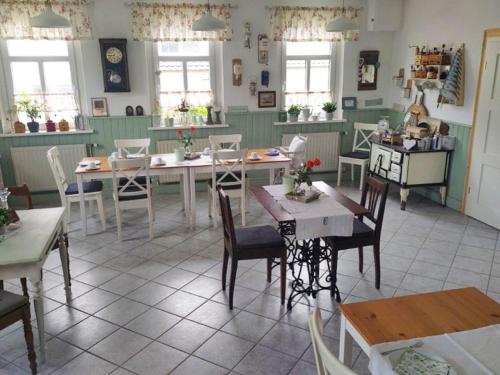 una sala da pranzo con tavoli, sedie e finestre di Pension Gute Stube a Sulzfeld