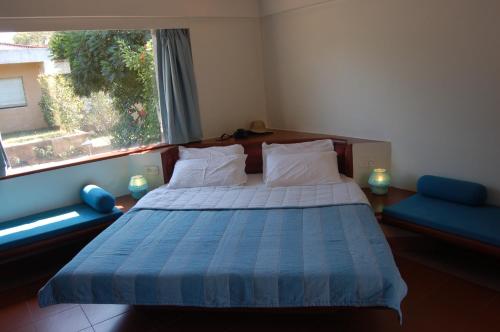 a bedroom with a bed with a blue blanket and a window at The Meadows Resort and Spa in Aurangabad