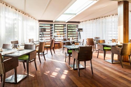 ポルテ・シュル・ガロンヌにあるLe Trèfleのテーブルと椅子、大きな窓のあるレストラン