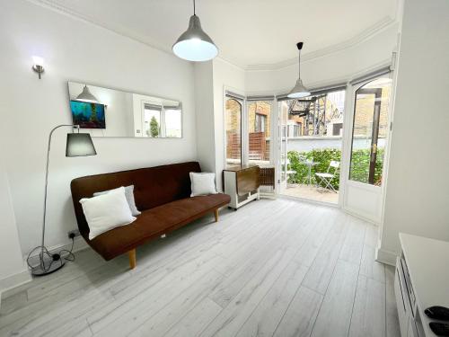 uma sala de estar com um sofá castanho e algumas janelas em LUXURIOUS Terrace 2 Bedrooms in Relaxing Covent Garden Apartment em Londres