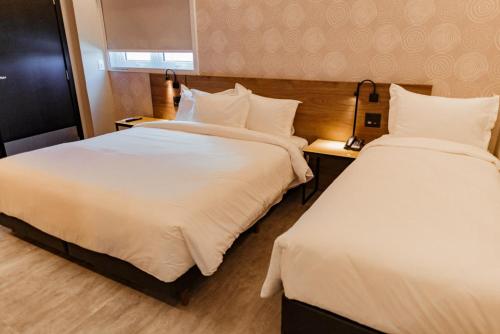 a hotel room with two beds with white sheets at Tru By Hilton Criciúma in Criciúma