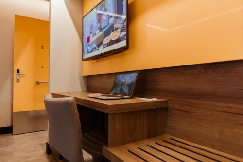 a laptop on a desk with a tv on a wall at Tru By Hilton Criciúma in Criciúma