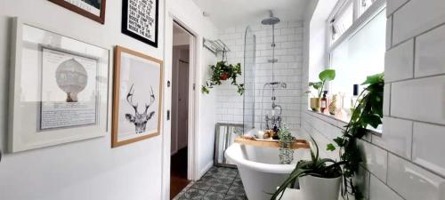 a bathroom with a white tub and plants in it at Stylish 3 Bedroom Townhouse in Brockley with Large Garden in London